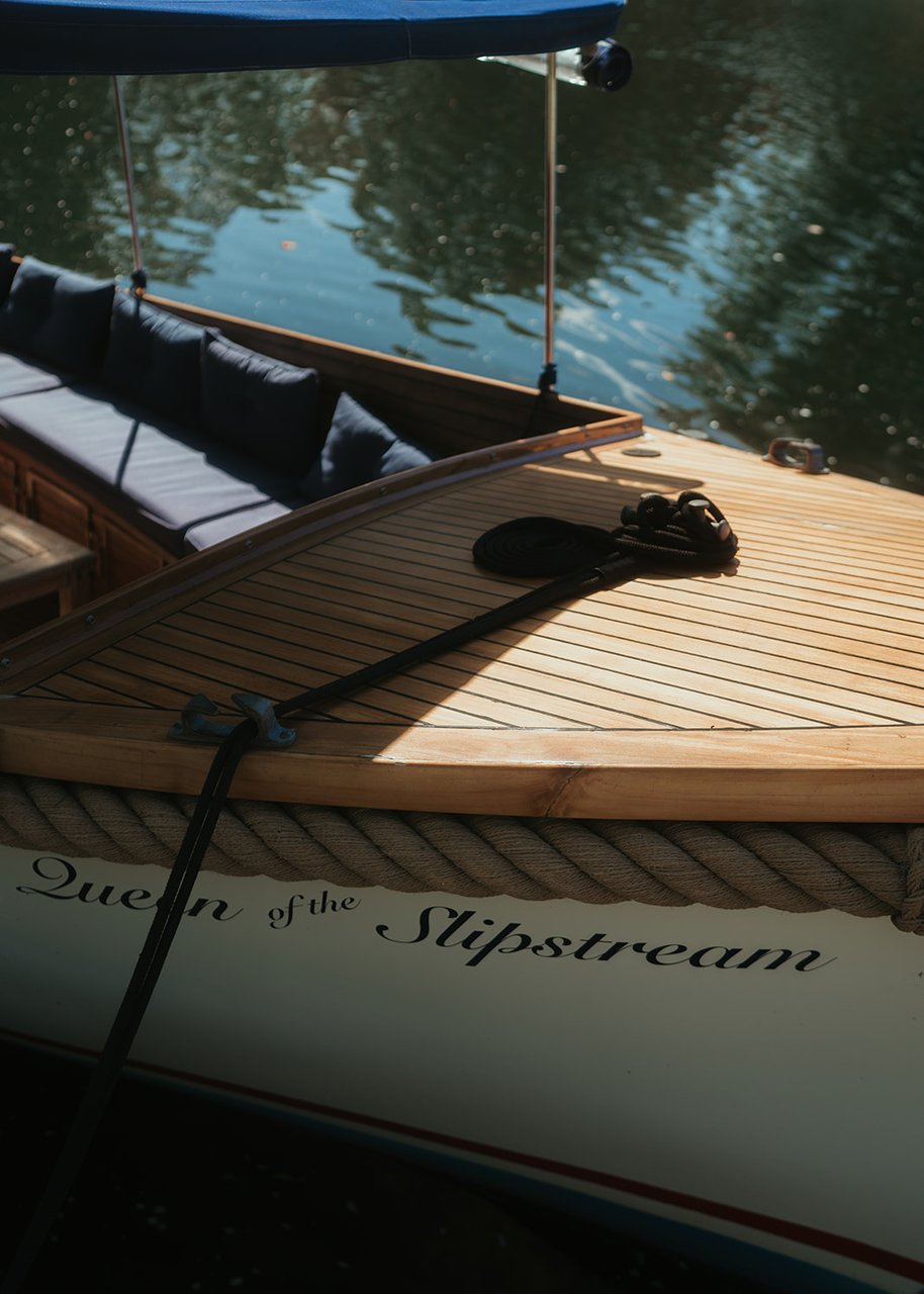The varnished teak foredeck and hand-lettered name of Queen of the Slipstream