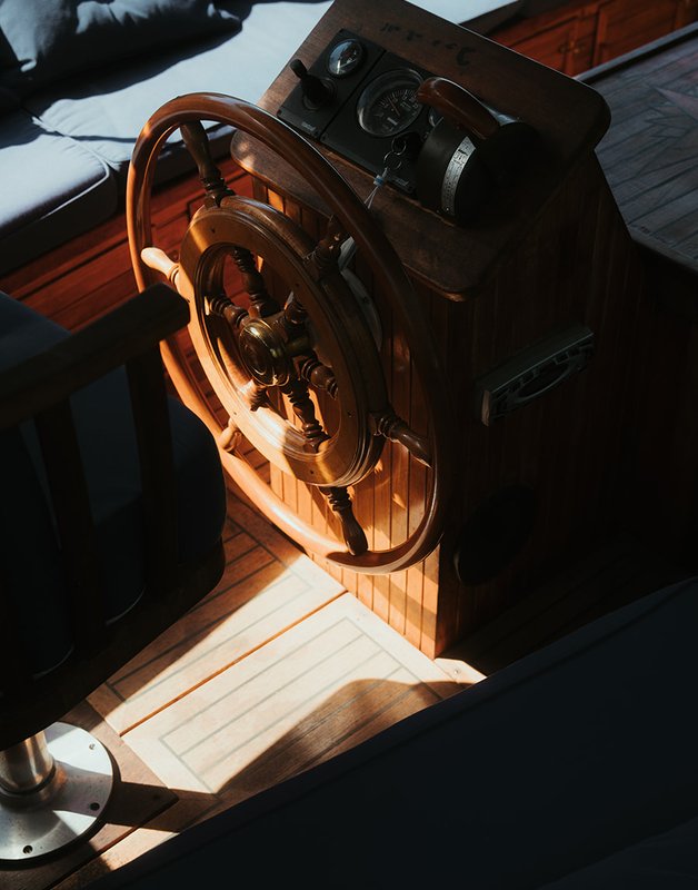 Sunlight falling on the traditional wooden ship's wheel at the helm