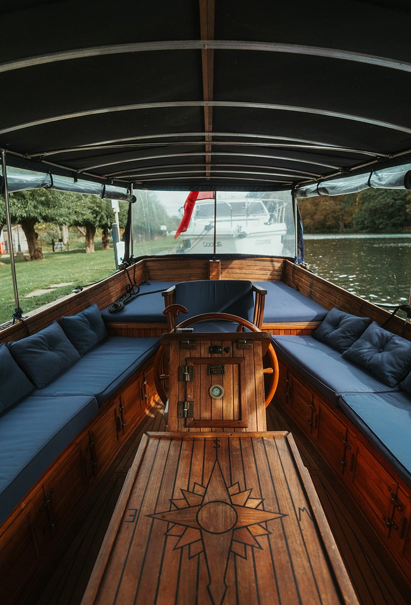 The canopied interior of Queen of the Slipstream with navy banquette seating and a compass-rose table
