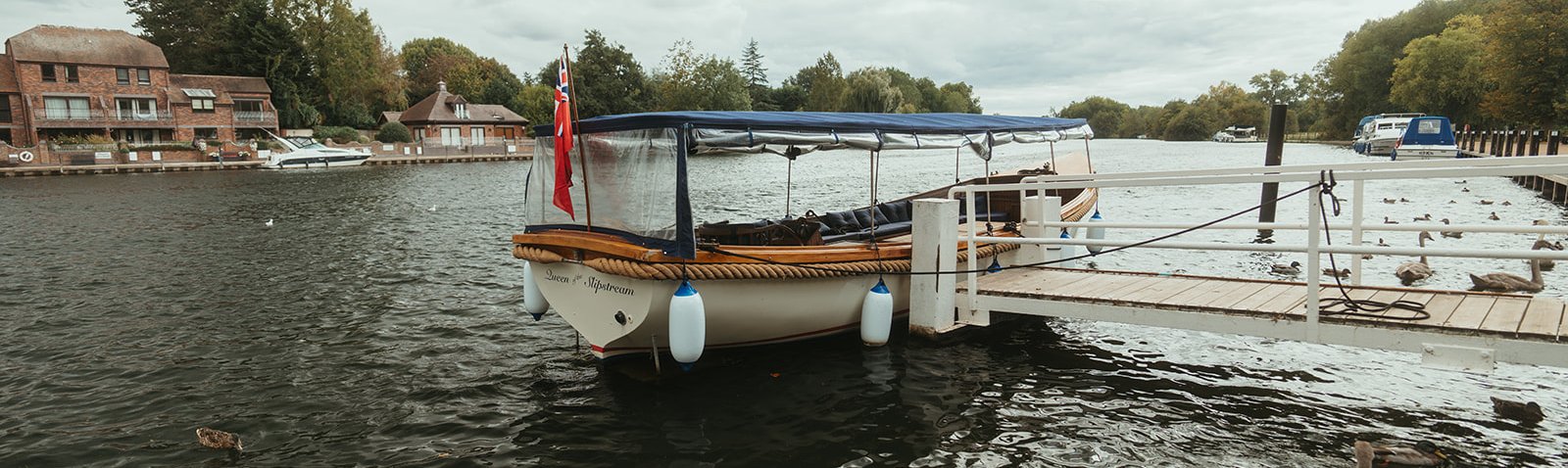 Queen of the Slipstream flying the red ensign at her jetty on the Thames at Marlow