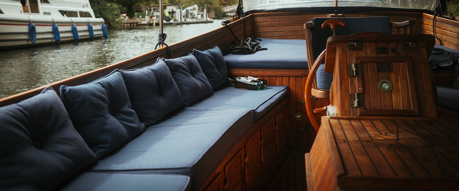 Navy cushioned seating and wine aboard Queen of the Slipstream on the river